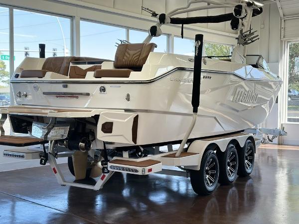 Malibu 25 LSV 2025 Malibu 25 LSV boat on trailer, showcased indoors with sleek design and modern features.