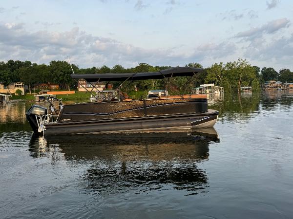 Premier 250 Solaris RL 2025 Premier 250 Solaris RL pontoon boat on a calm lake with scenic background.