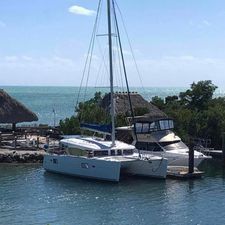 Lagoon 400 Owner's Version NEW ENGINES 2010 Lagoon 400 catamaran docked by the sea, clear sky, and lush greenery.