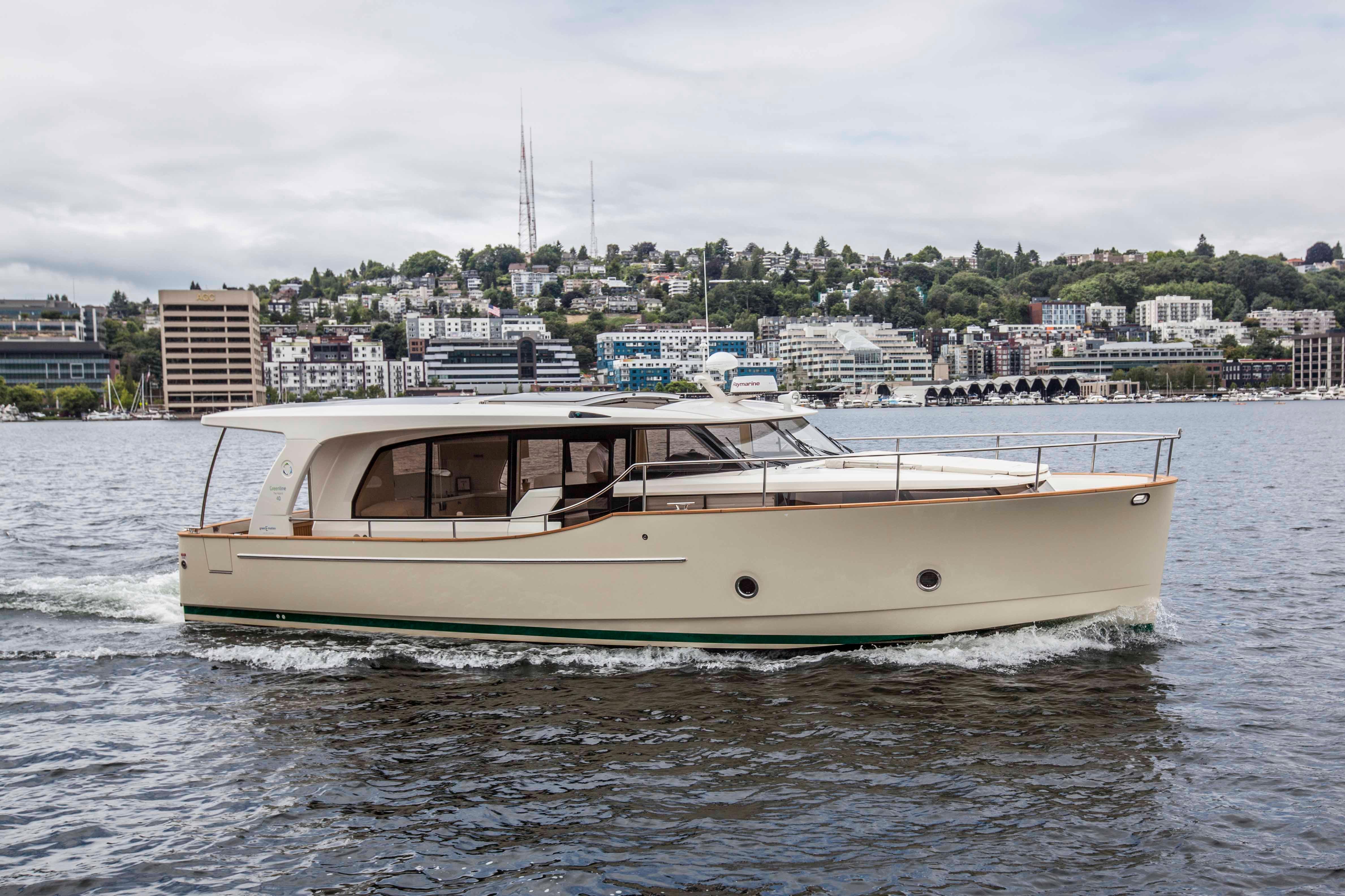Greenline 40 2014 Greenline 40 yacht cruising on a scenic waterfront with city skyline backdrop.