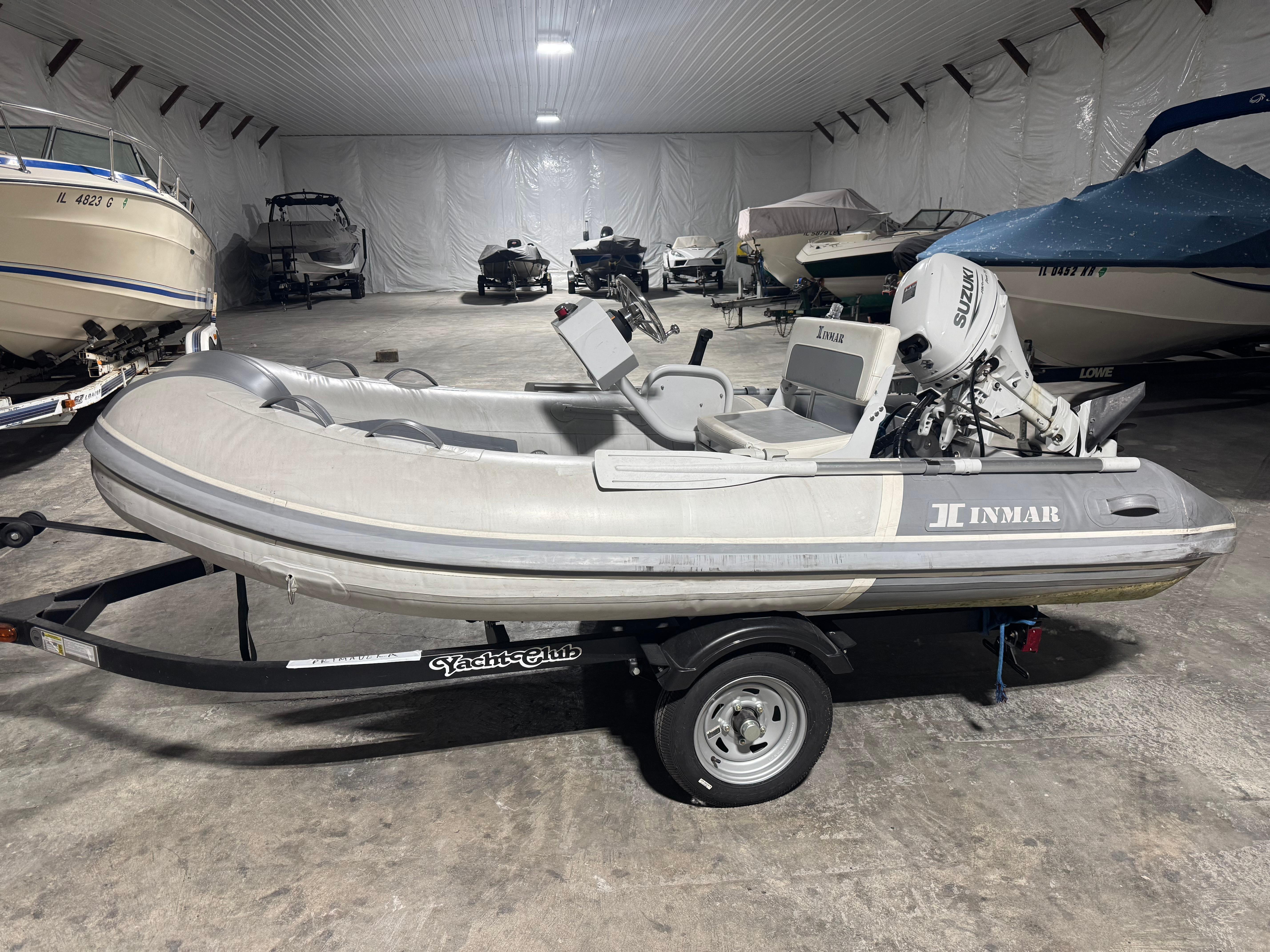 Inmar Aluma Lite 325R 2021 Inmar Aluma Lite 325R inflatable boat in storage, featuring Suzuki outboard motor.