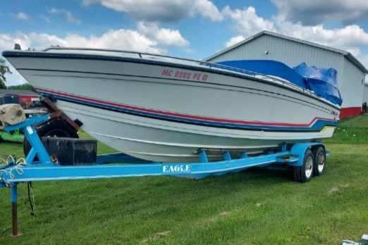 Formula 272 SR-1 1988 Formula 272 SR-1 boat on blue trailer, parked on grass under cloudy sky.