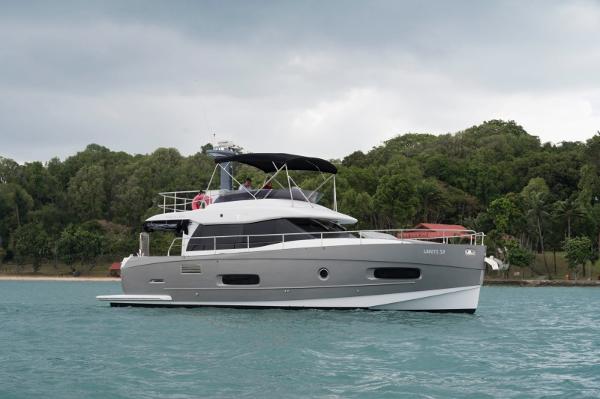 Azimut Magellano 2017 Azimut Magellano yacht cruising near a lush, green shoreline under a cloudy sky.