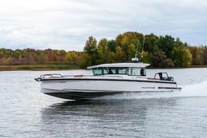Axopar 37 XC CROSS CABIN 2022 Axopar 37 XC CROSS CABIN cruising on a lake with autumn trees in the background.