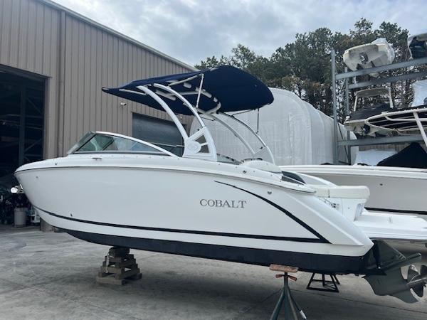 Cobalt R5 2018 Cobalt R5 boat with blue canopy, displayed outdoors near a warehouse.