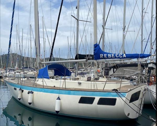 Oyster 39 1980 Oyster 39 sailboat docked in marina, featuring blue sail cover and white hull.