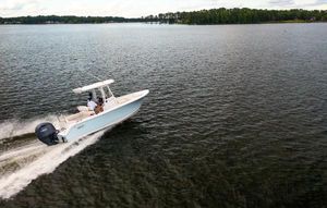 Sea Hunt Ultra 229 2025 Sea Hunt Ultra 229 boat cruising on a serene lake.