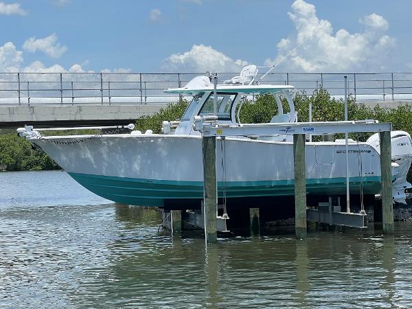 Sportsman 302cc 2025 Sportsman 302cc boat docked on lift near bridge, under blue sky.