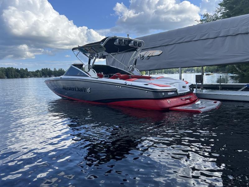 MasterCraft X55 2015 MasterCraft X55 boat docked on a calm lake under a cloudy sky.