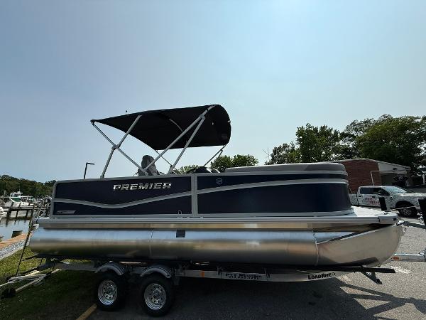 Premier 200 Sunscape RE XLC Tritoon 2025 Premier 200 Sunscape RE XLC pontoon boat on trailer, black canopy, parked outdoors.