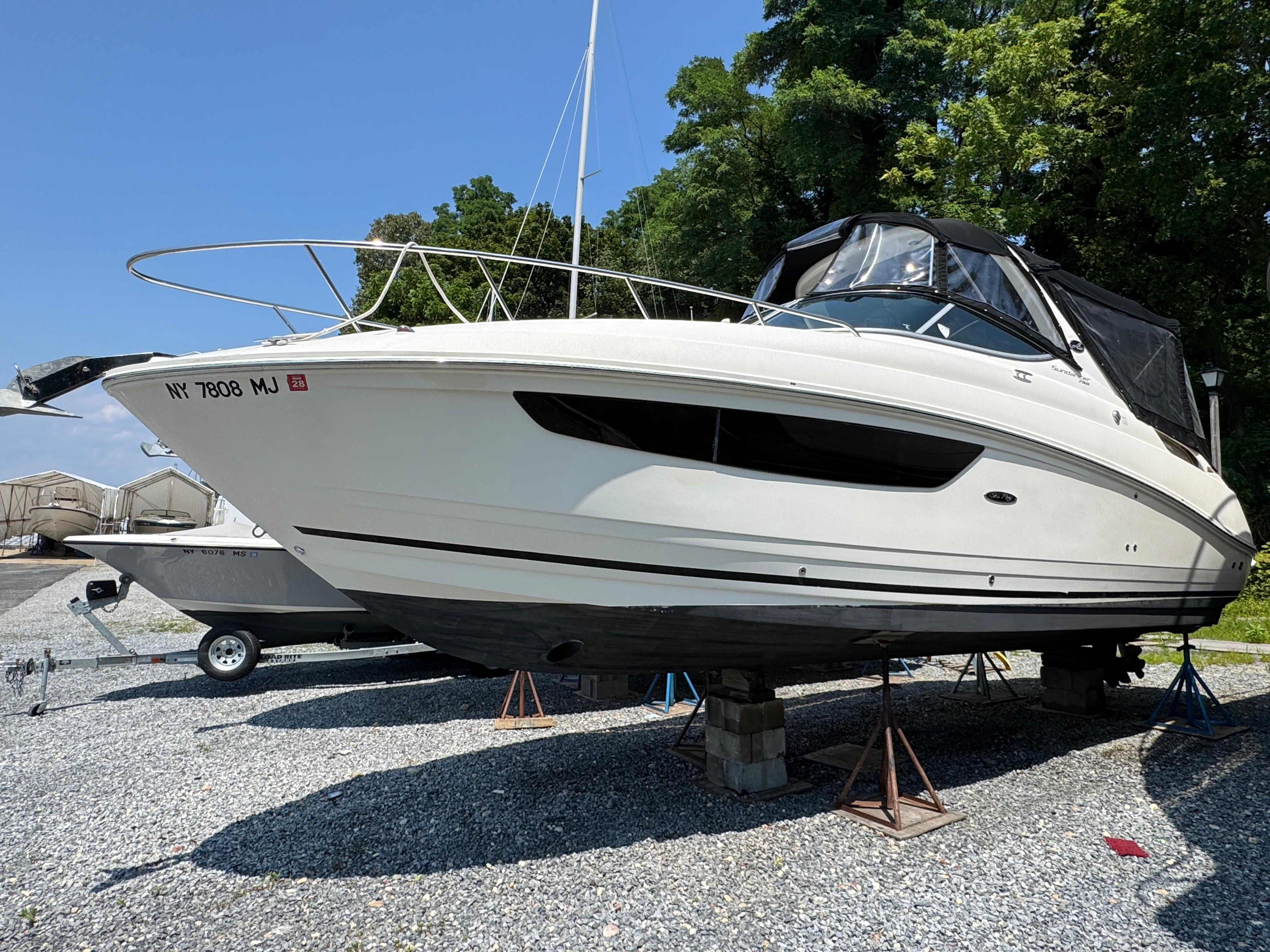Sea Ray 280 Sundancer 2014 Sea Ray 280 Sundancer boat on stands, outdoors, with trees in the background.