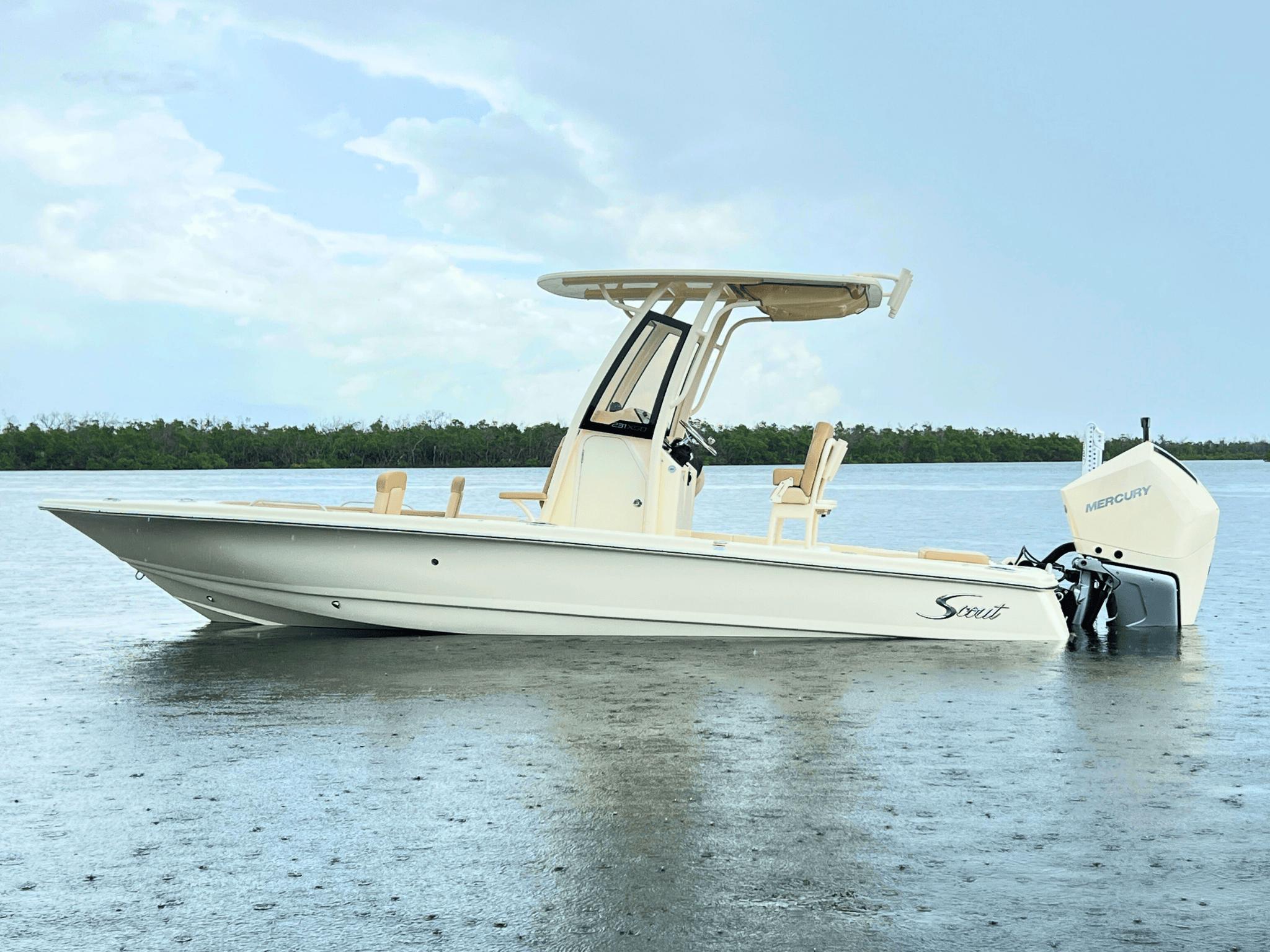 Scout 231 XSB 2025 Scout 231 XSB boat on calm water with Mercury engine, under cloudy sky.