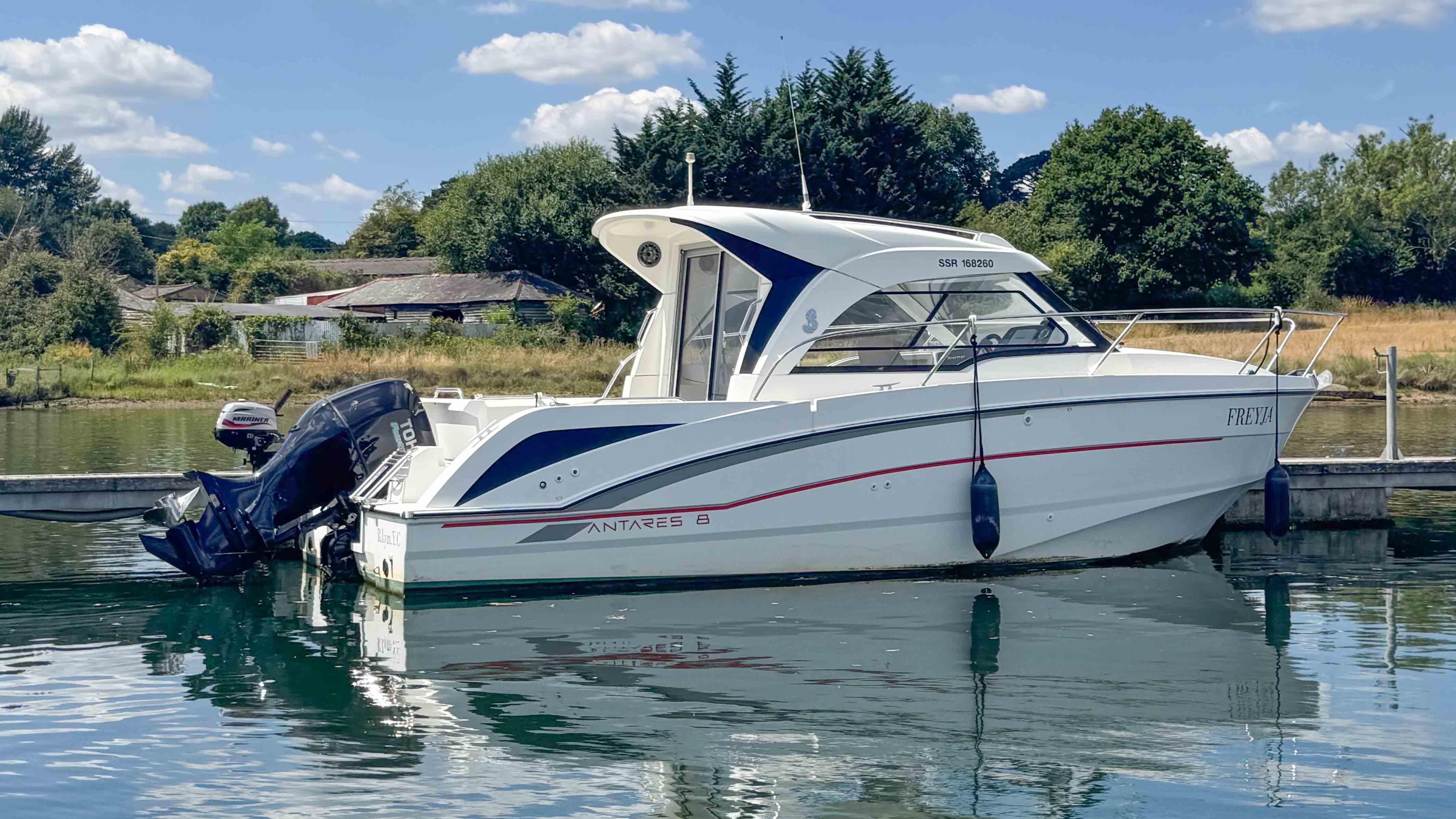 Beneteau Antares 8 2017 Beneteau Antares 8 boat docked on a calm lake with scenic background.
