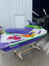 Kawasaki ZXI 900 1996 Kawasaki ZXI 900 jet ski with vibrant purple and green design in a garage.