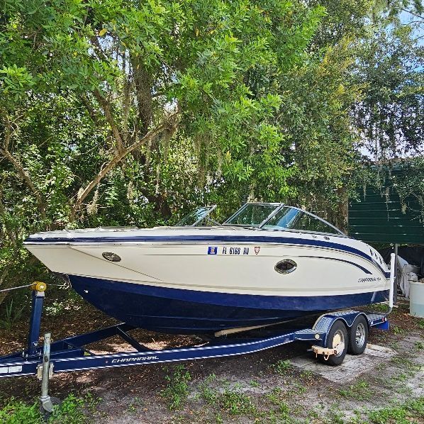 Chaparral 246 SSi 2013 Chaparral 246 SSi boat on trailer, parked outdoors near trees.