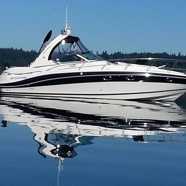 Four Winns 350 2006 Four Winns 350 boat on calm water, reflecting clear blue sky.