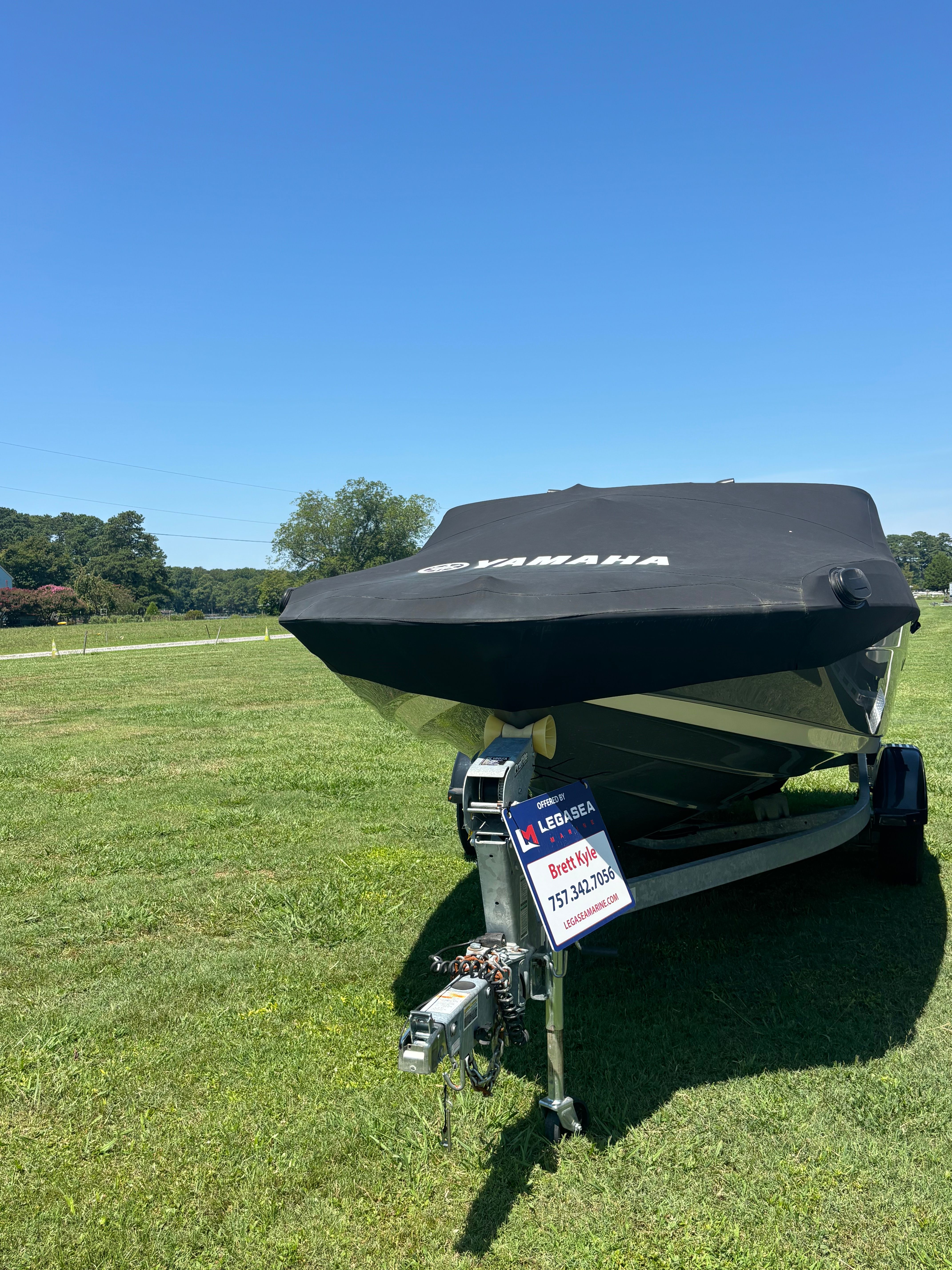 Yamaha Boats SX 190 2021 Yamaha SX 190 boat on trailer, covered, in grassy field under clear blue sky.