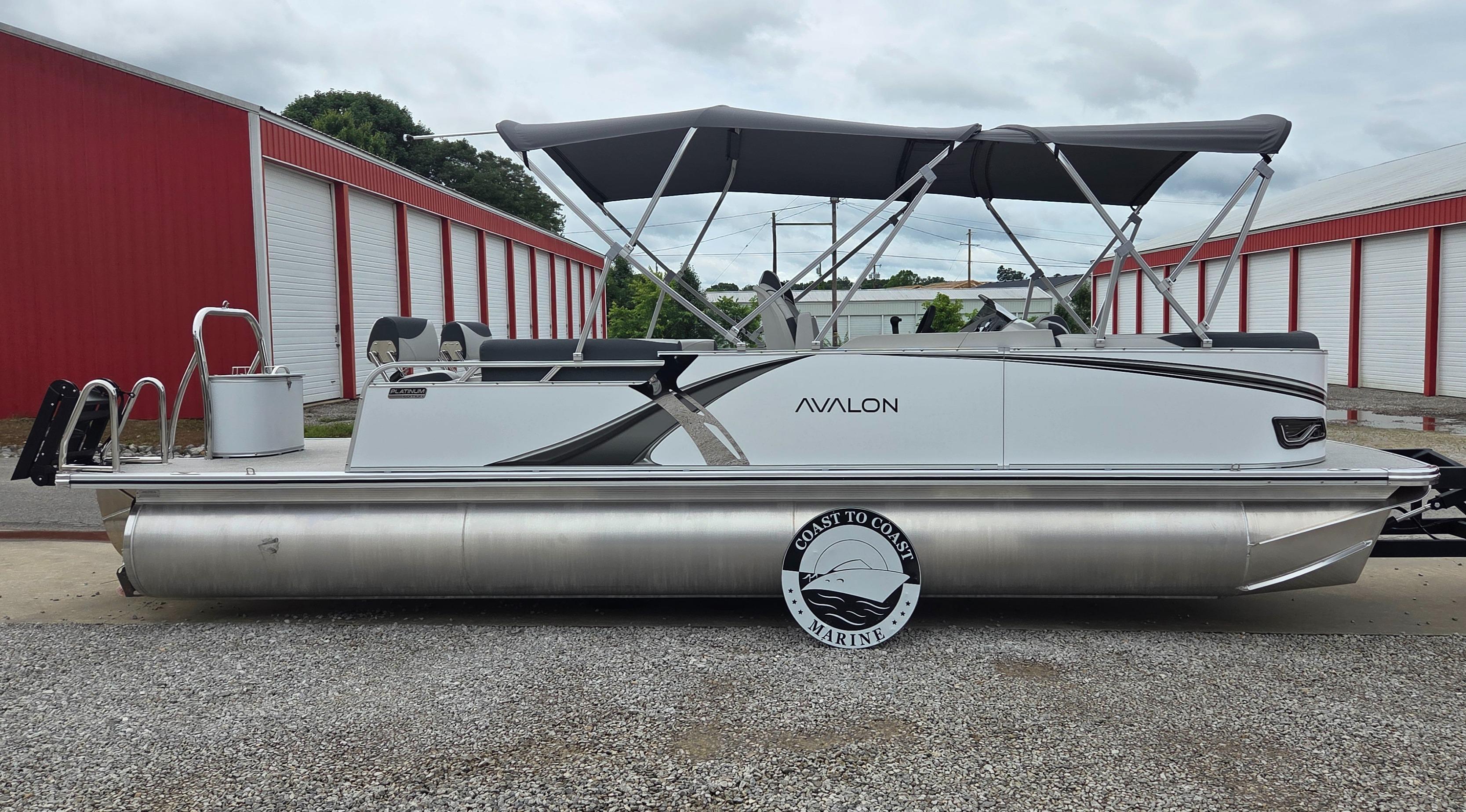 Avalon Platinum LSZ 2585 Quad Lounger Shift 2025 Avalon Platinum LSZ 2585 Quad Lounger Shift pontoon boat, parked near red storage units.