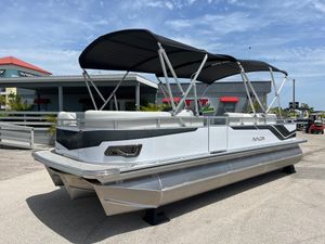 Avalon 2385 Venture 85 Rear Fish, Tri Toon, High Performance 2025 Avalon 2385 Venture 85 Tri Toon boat with canopy, parked outdoors.