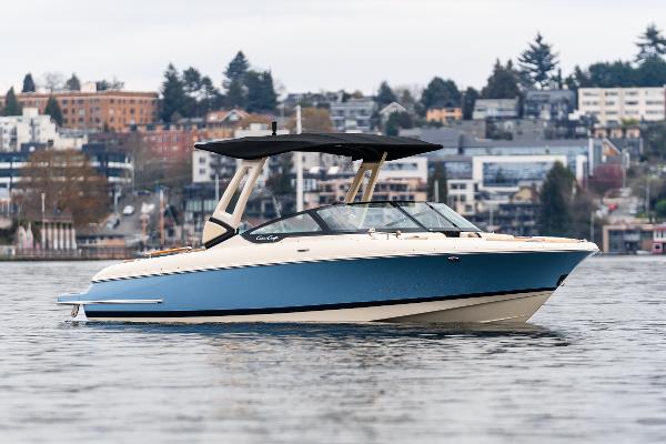 Chris-Craft Sportster 25 2025 Chris-Craft Sportster 25 boat on calm water with urban backdrop.