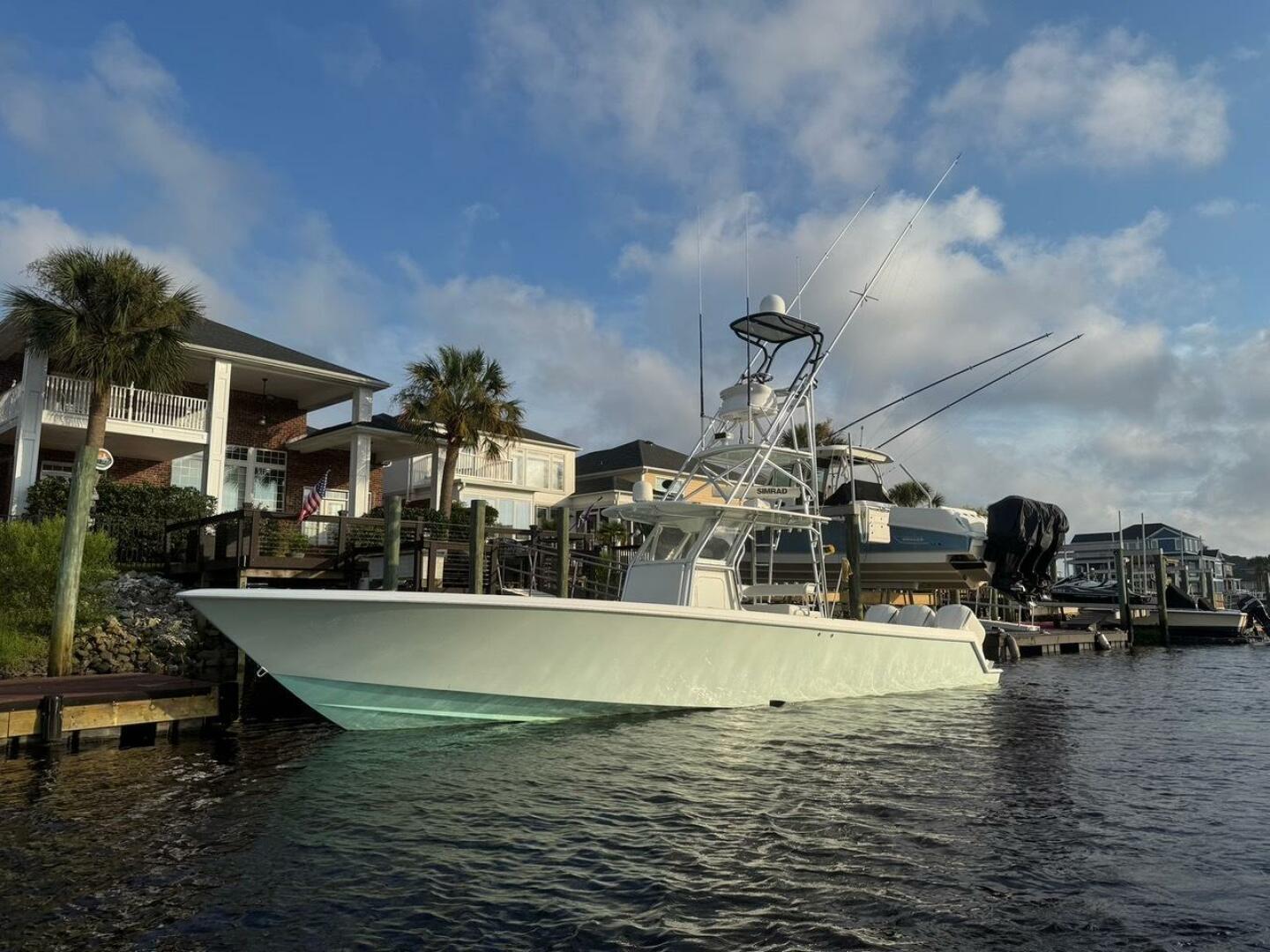 Contender 39 ST 2012 Contender 39ST boat docked by waterfront homes under a blue sky.