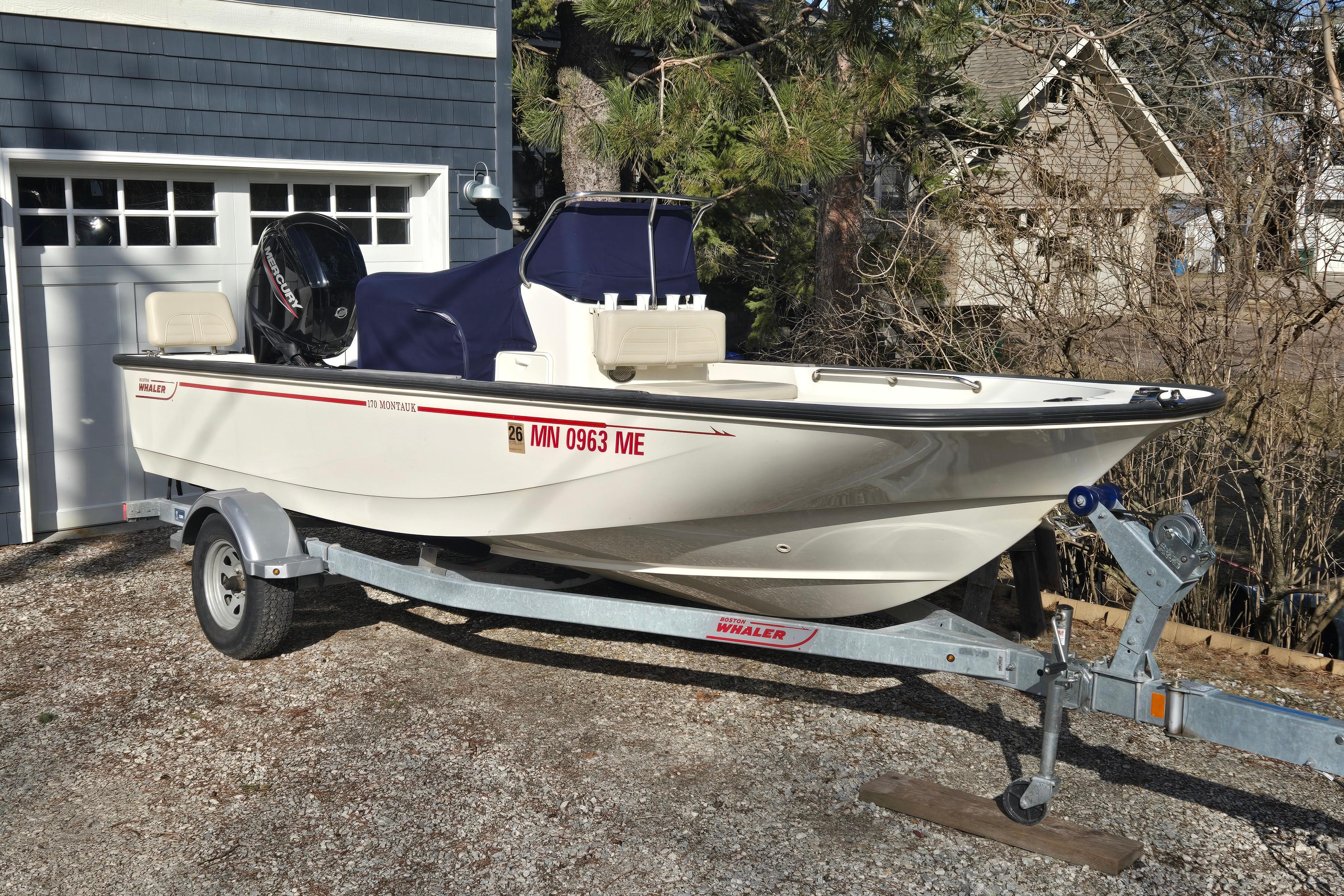 Boston Whaler 17 Montauk 2021 Boston Whaler 17MTK boat on trailer, parked outside a garage.