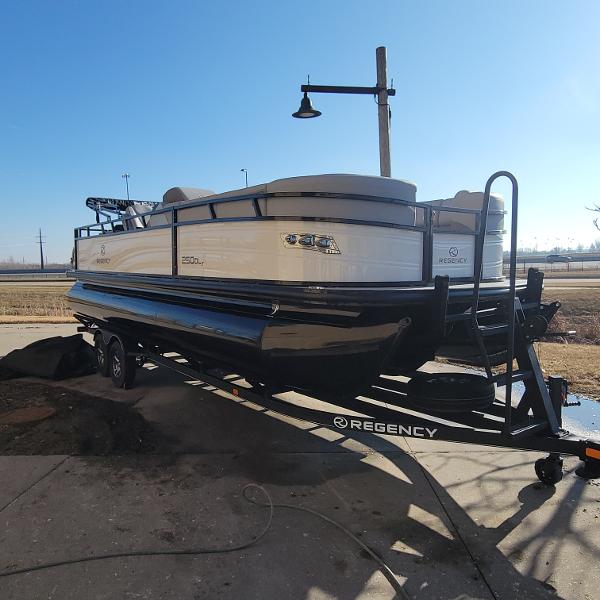 Regency 250 DL3 2024 Regency 250 DL3 pontoon boat on trailer in outdoor setting.