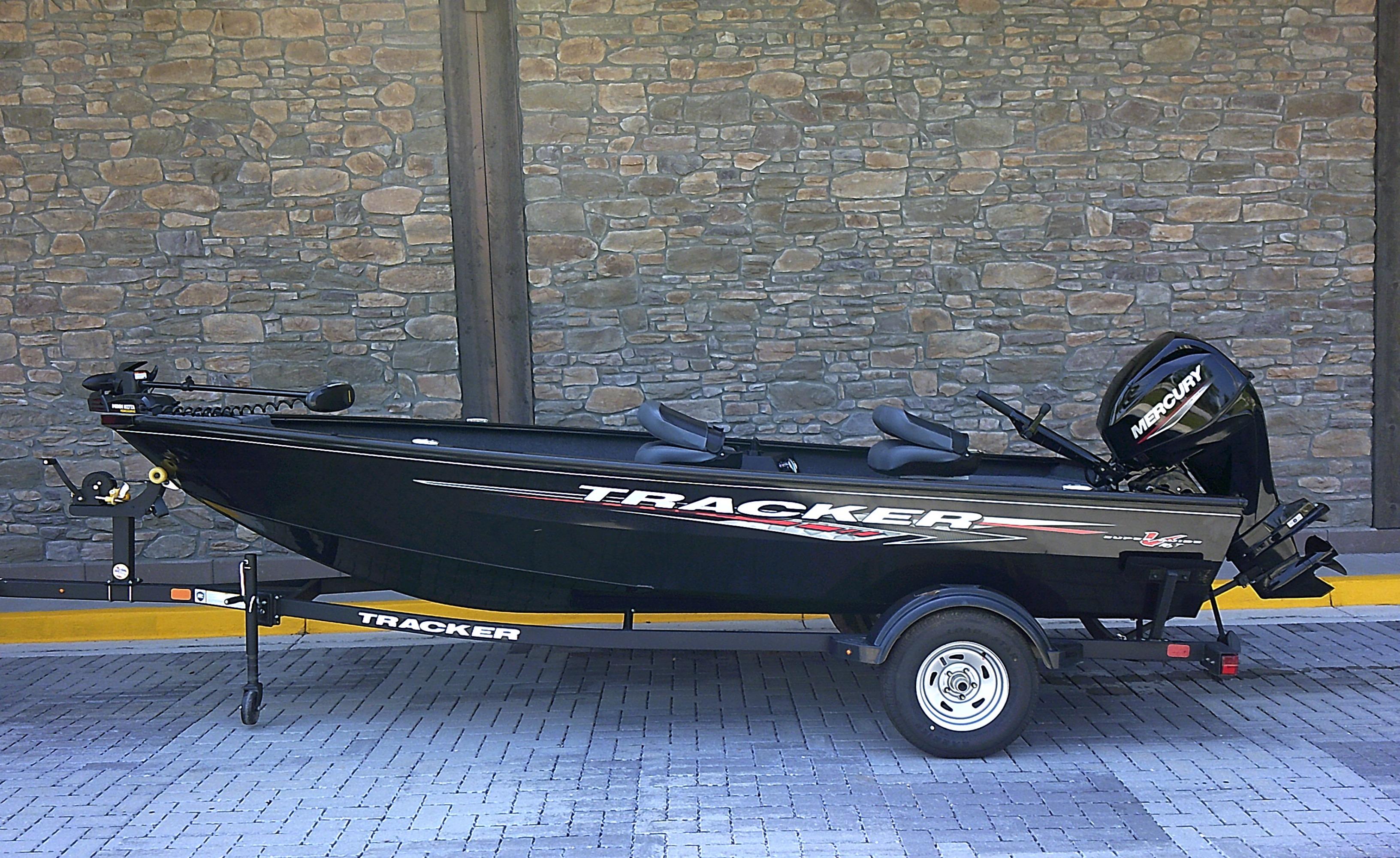 Tracker Super Guide V-16 T 2025 Tracker Super Guide V-16 T boat on trailer, parked against stone wall.