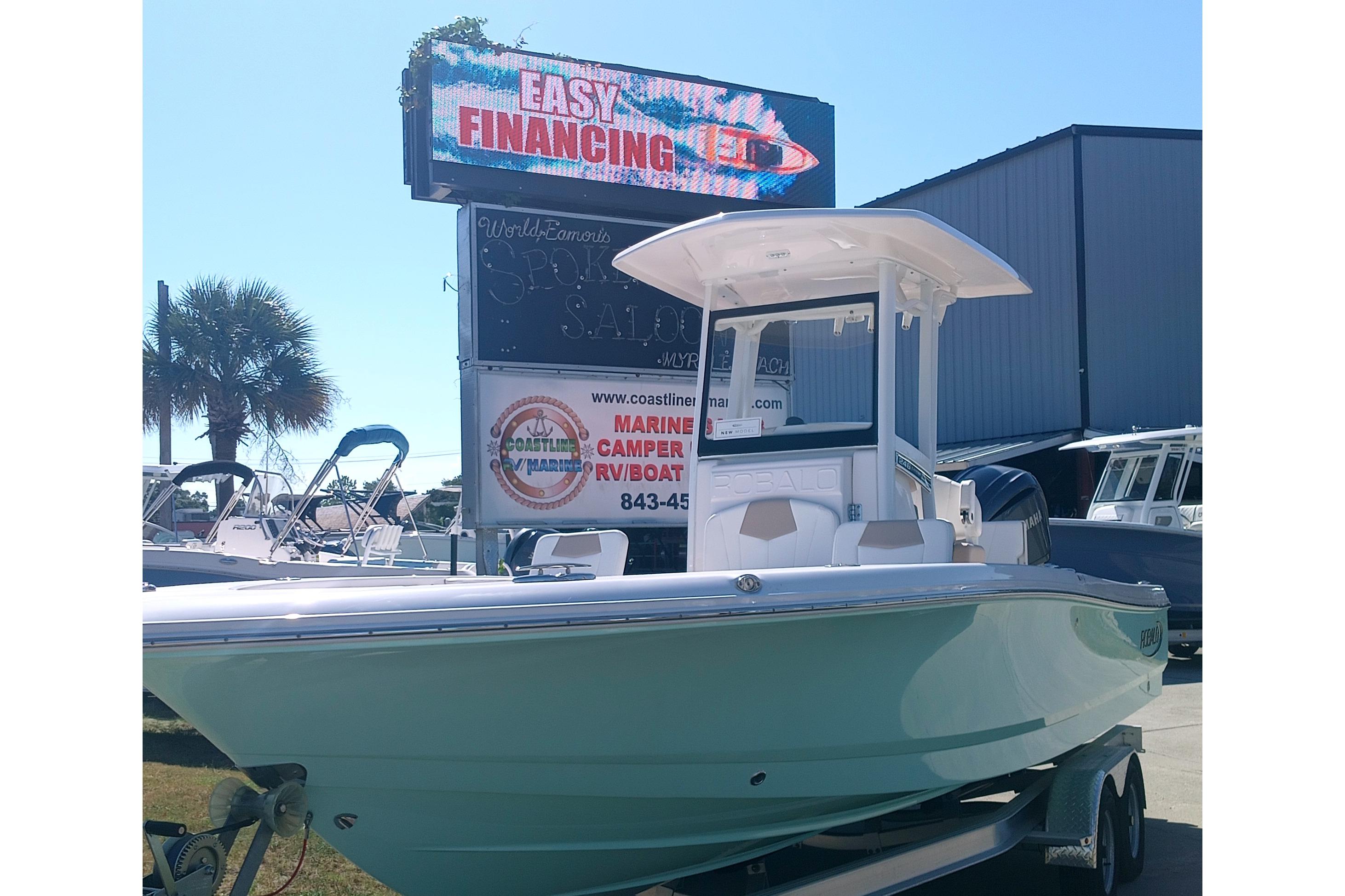 Robalo 246 Cayman 2024 Robalo 246 Cayman boat on trailer, dealership background, easy financing sign.