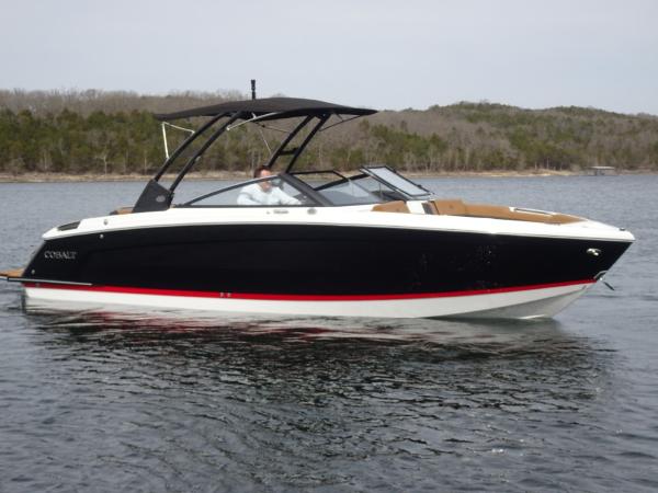 Cobalt R8 2025 Cobalt R8 boat on a calm lake with forested shoreline.