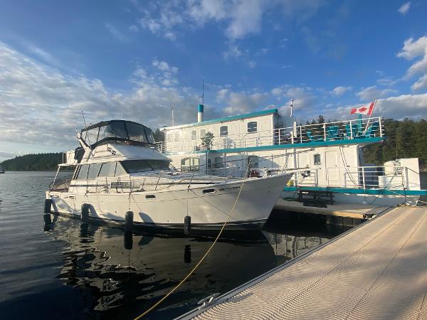 Bayliner 3888 Motoryacht 1991 Bayliner 3888 Motoryacht docked beside a houseboat under a blue sky.