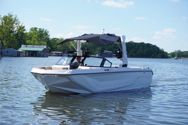 Nautique GS24 2025 Nautique GS24 boat on a calm lake with trees and docks in the background.