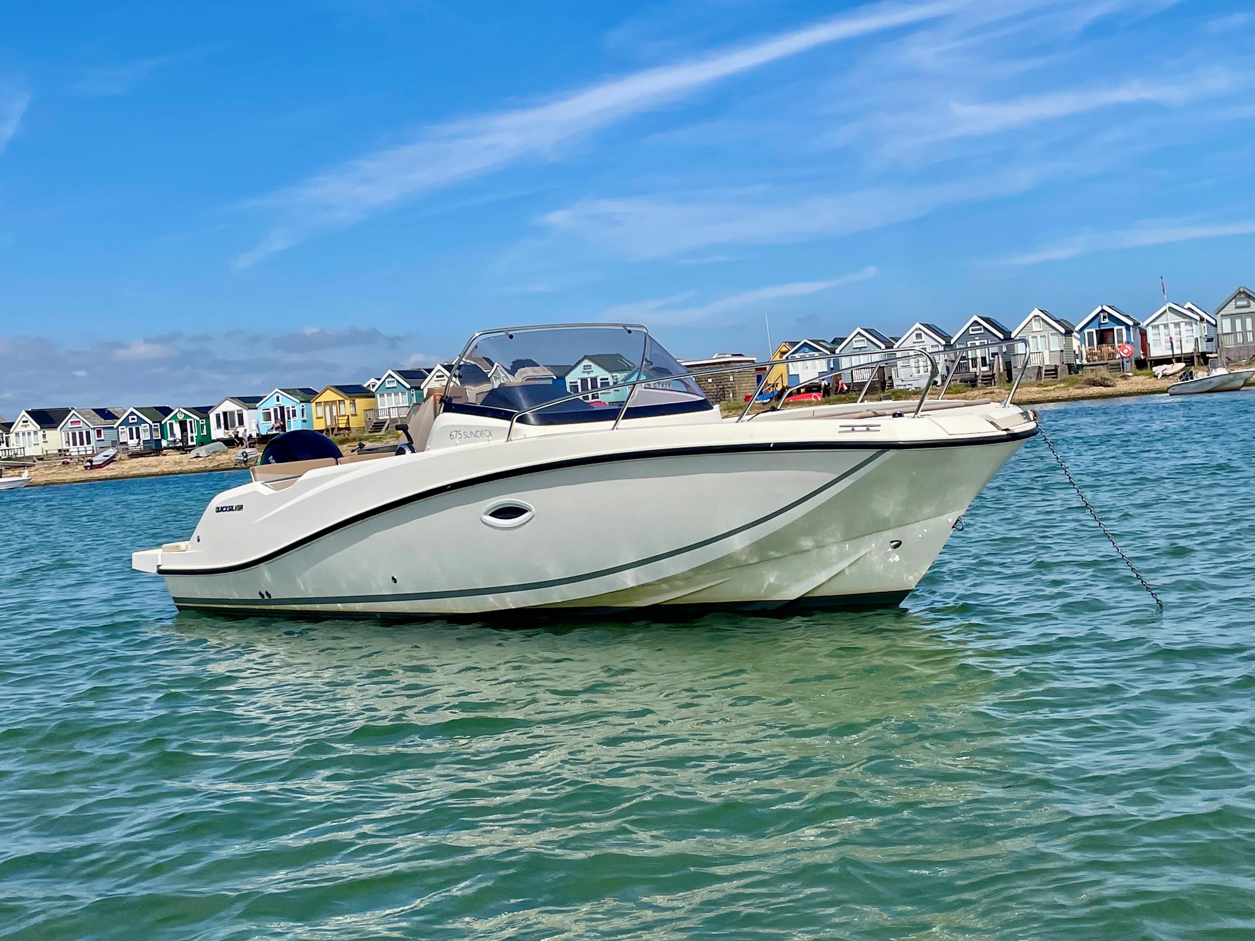 Quicksilver Activ 675 Sundeck 2022 Quicksilver Activ 675 Sundeck boat anchored near colorful beach houses.
