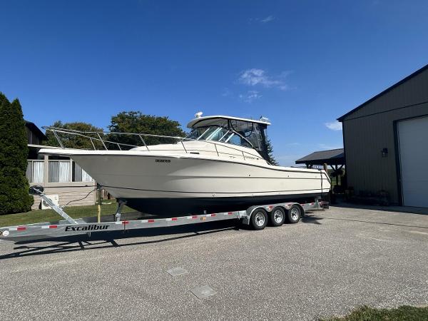 Pursuit 3070 Pursuit 2001 Pursuit 3070 boat on Excalibur trailer, parked outdoors under clear blue sky.