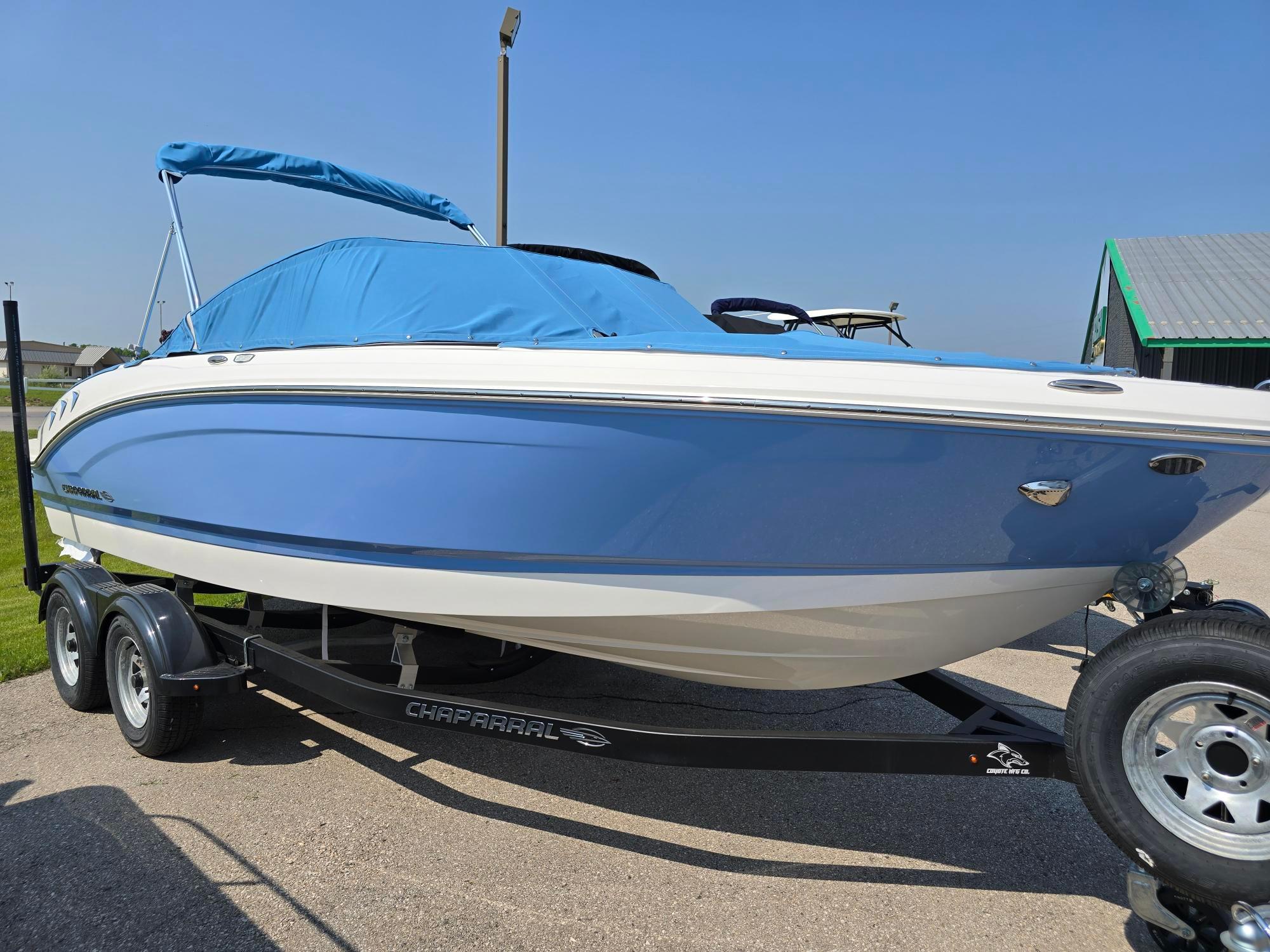 Chaparral 21 SSi 2025 Chaparral 21 SSi boat with blue cover on trailer, sunny day.