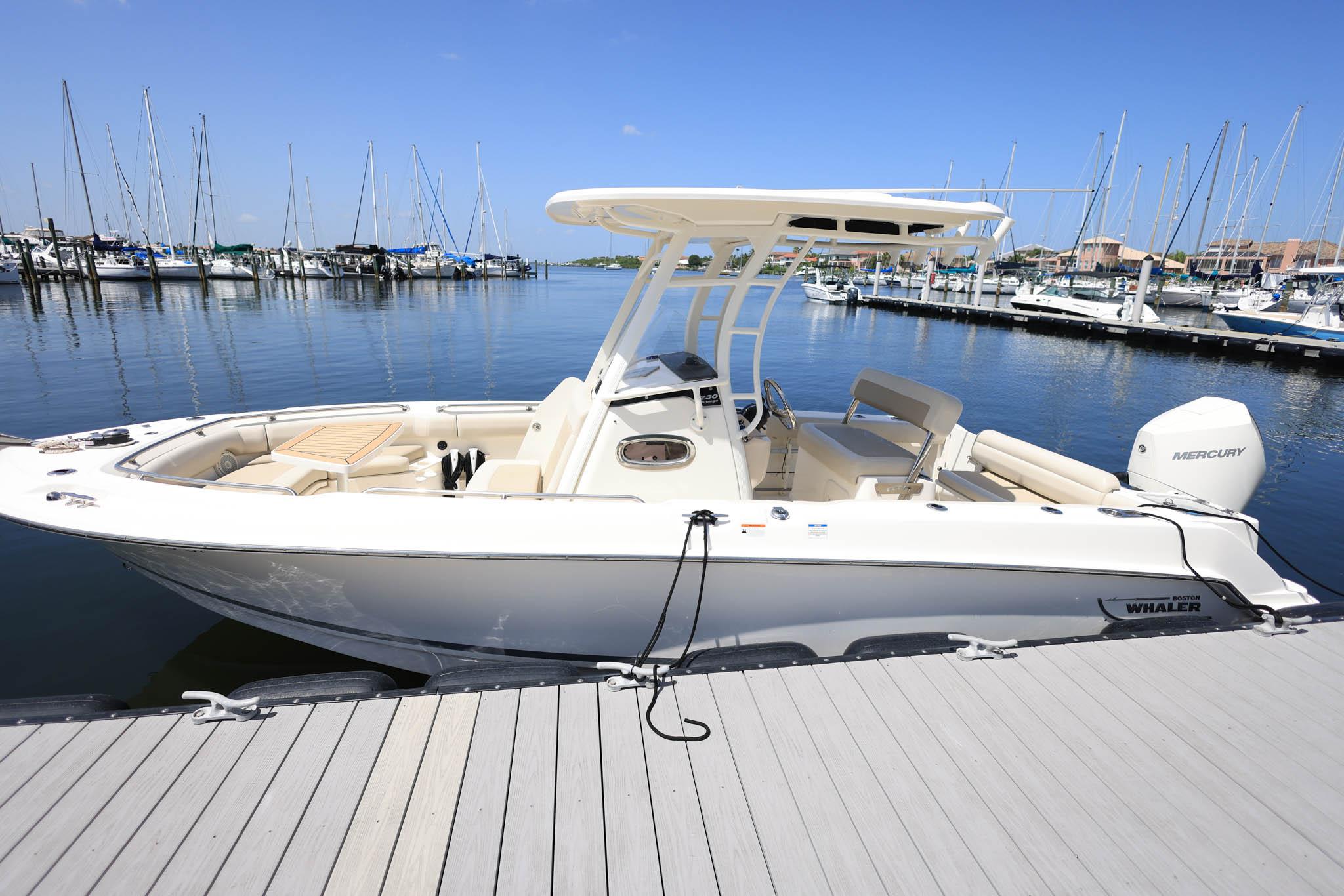 Boston Whaler 230 Outrage 2020 Boston Whaler 230 Outrage boat docked at marina with clear blue sky.