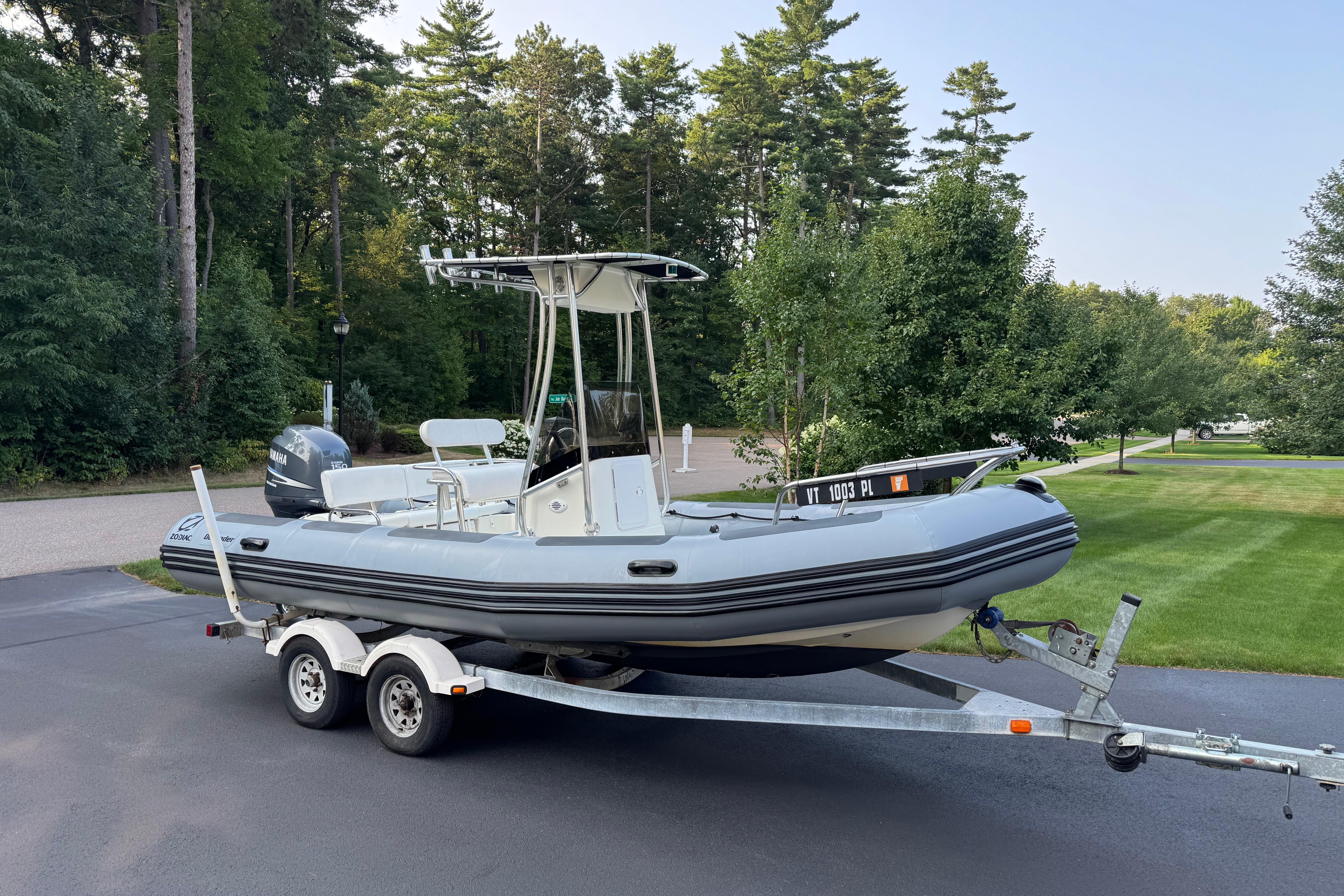 Zodiac Pro Open 650 2010 Zodiac Pro Open 650 boat on trailer, parked in a driveway with lush greenery.