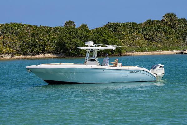 Century 3200 Center Console 2019 Century 3200 Center Console boat on calm water near lush shoreline.