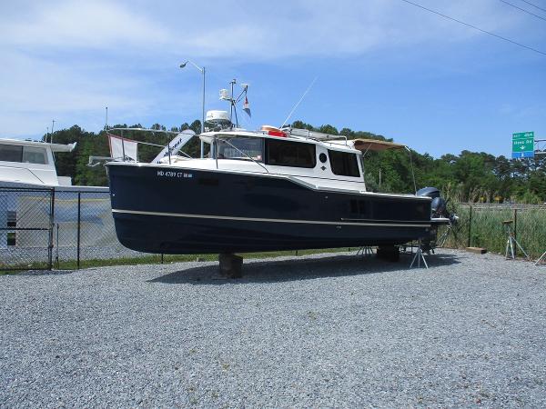 Ranger Tugs R-27 Luxury Edition 2020 Ranger Tugs R-27 LE boat on gravel lot, surrounded by fence and trees.
