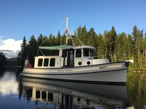 Nordic Tug 32 2002 Nordic Tug 34 boat "Misty" on calm water, surrounded by trees.