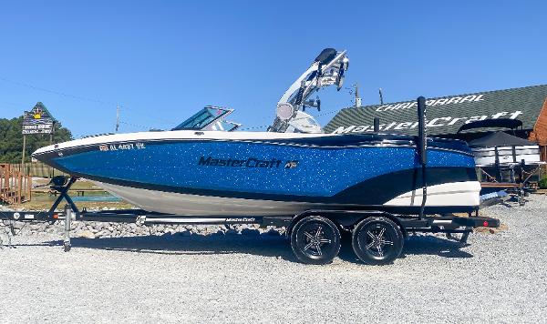 MasterCraft XT22 2021 MasterCraft XT22 boat on trailer, blue and white design, parked outdoors.
