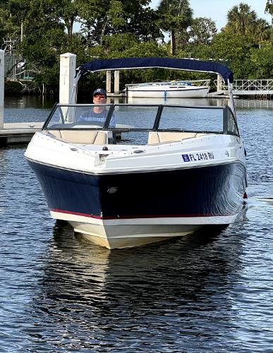 Rinker Q5 BR 2018 Rinker Q5 BR boat on water, with a person onboard, surrounded by trees and docks.