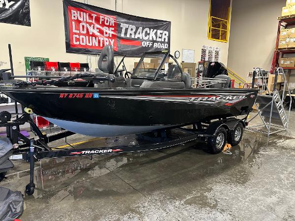 Tracker Targa V-18 WT 2023 Tracker Targa V-18 WT boat on trailer in showroom with promotional banner.