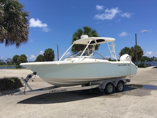 Key West 239 DFS 2016 Key West 239 DFS boat on trailer, parked near palm trees under blue sky.
