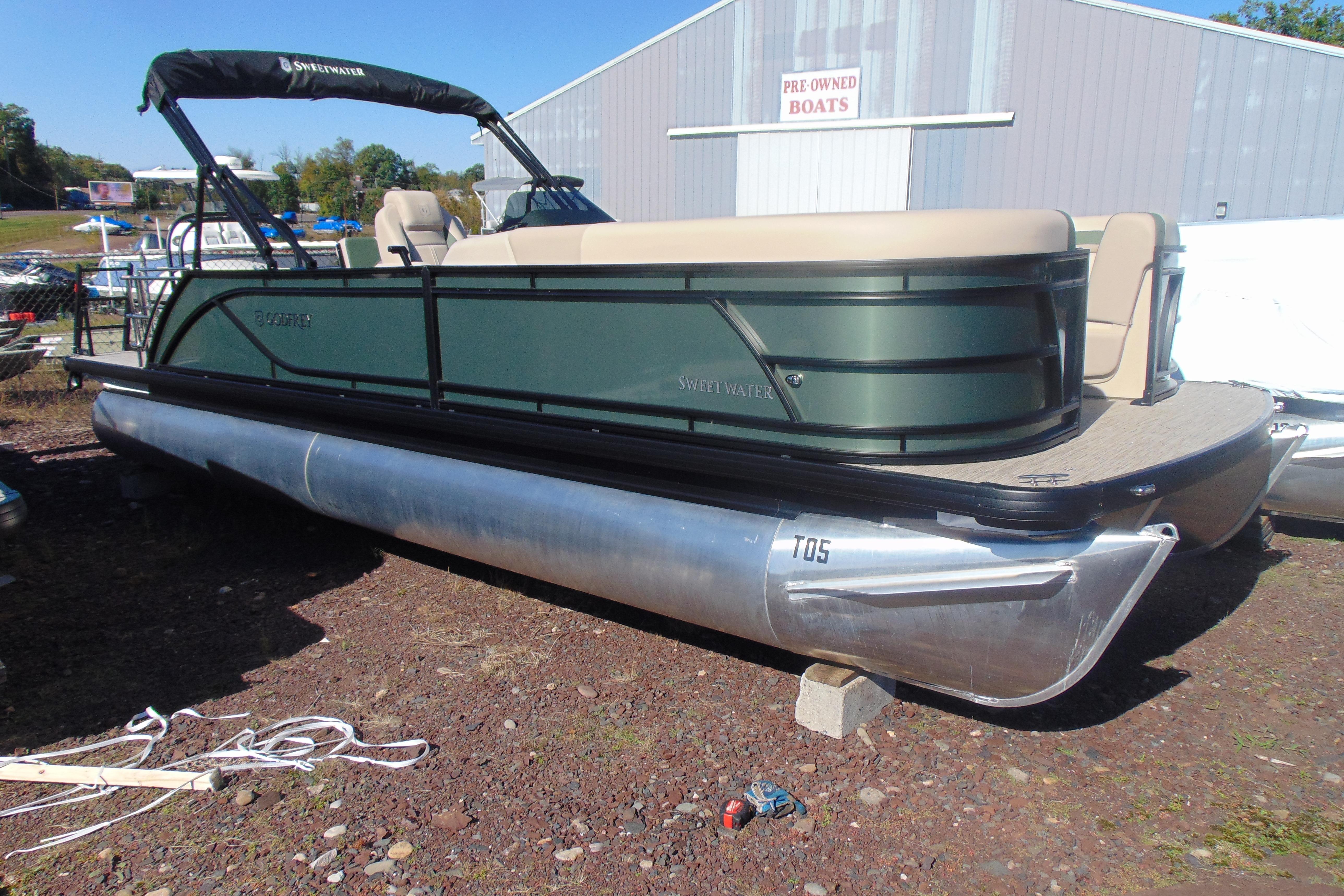 Godfrey SWEETWATER 2286 SFL 2026 Godfrey SWEETWATER 2286 SFL pontoon boat displayed outdoors near pre-owned boats.