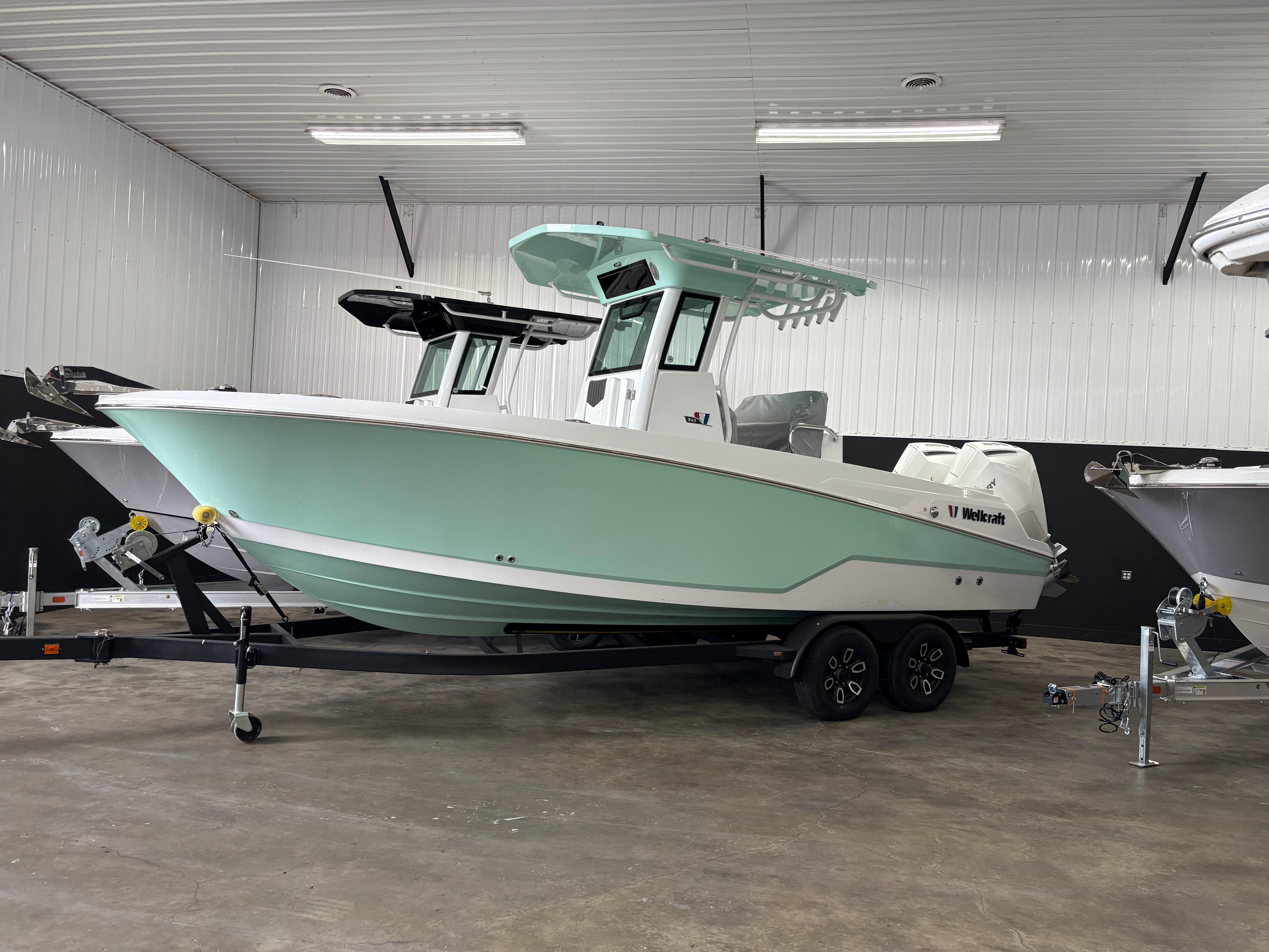 Wellcraft 243 Fisherman 2025 Wellcraft 243 Fisherman boat in a showroom, featuring a sleek design and mint green hull.