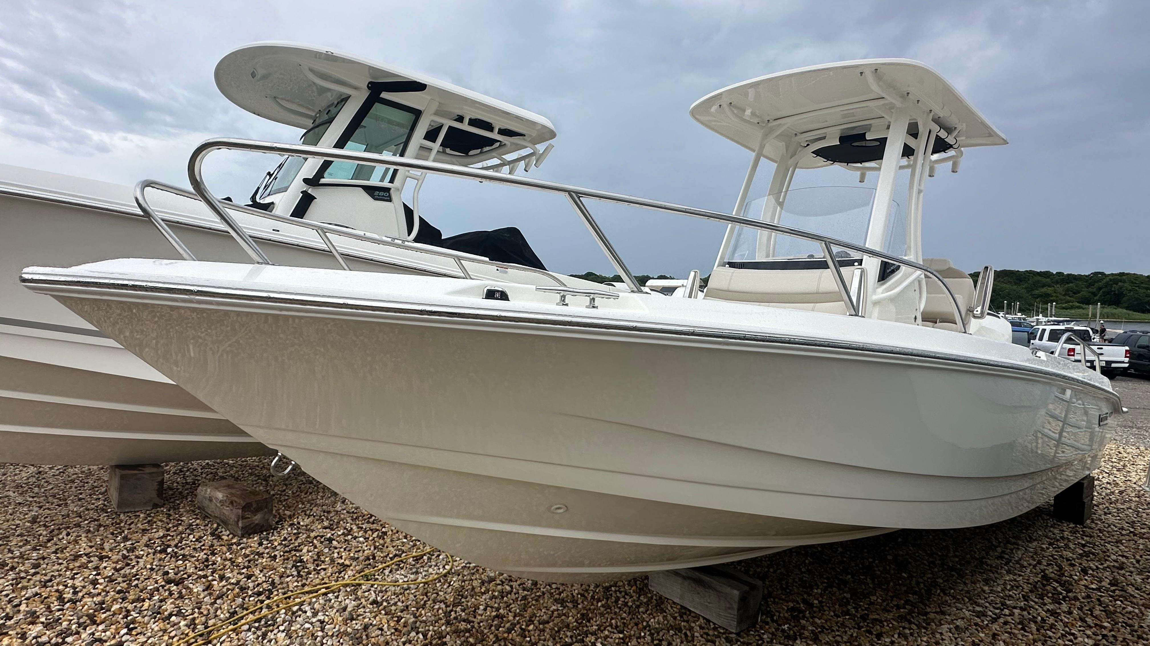 Boston Whaler 220 Dauntless 2024 Boston Whaler 220 Dauntless boat on gravel, showcasing sleek design and sturdy build.