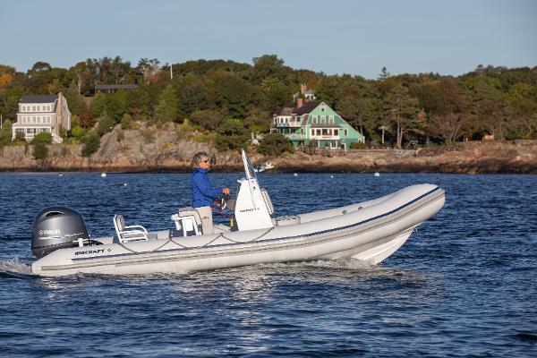 Ribcraft 5.85 2024 Ribcraft 5.85 boat cruising on a scenic lake near shoreline houses.