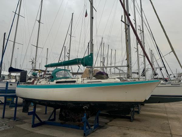 Moody 33 1980 Moody 33 sailboat on stands in a marina, overcast sky.
