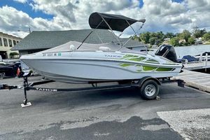 Tahoe T18 2022 Tahoe T18 boat on trailer, parked near a lake under cloudy sky.